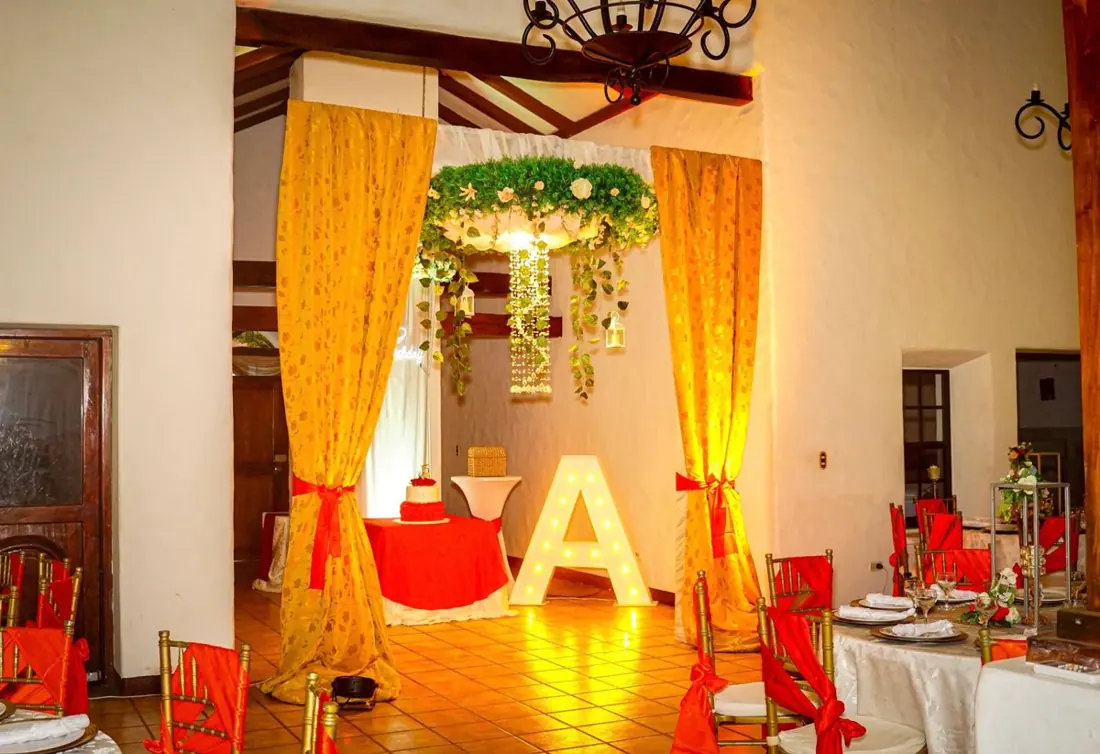 Cumpleaños en el Salón Colonial con cortinas doradas y letra A iluminada