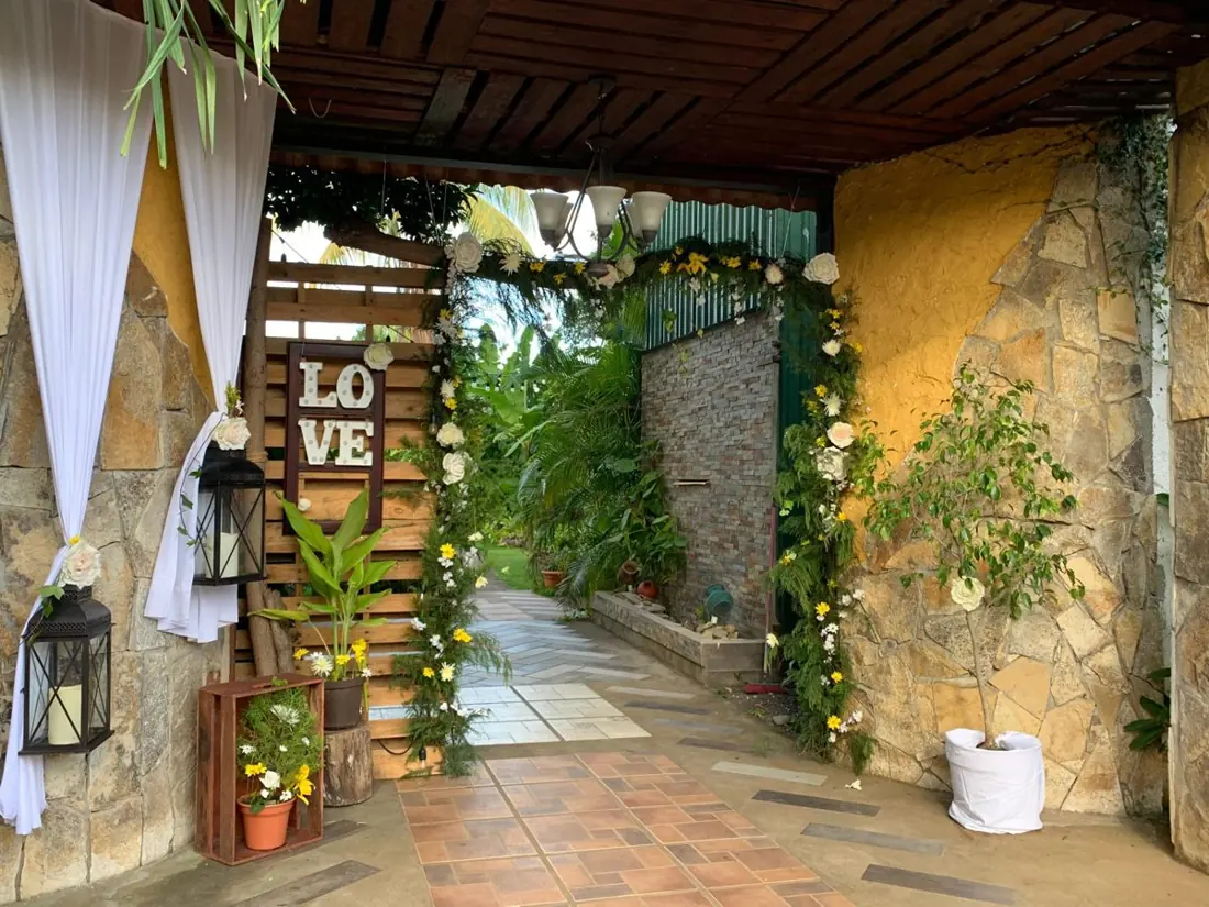 Entrada rústica con arco de flores, faroles y letras LOVE