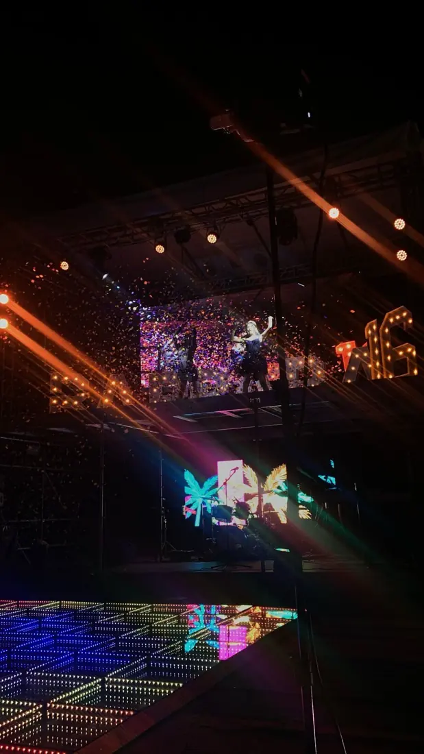 Escenario con pantallas, luces, confeti y pista LED en una fiesta