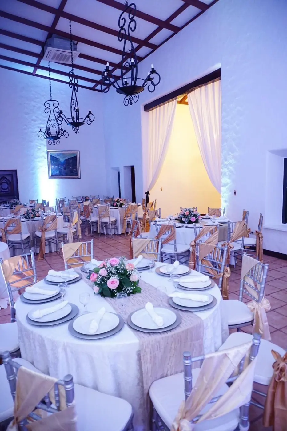 Salón Colonial con mesas redondas, sillas tiffany y candelabros de hierro forjado